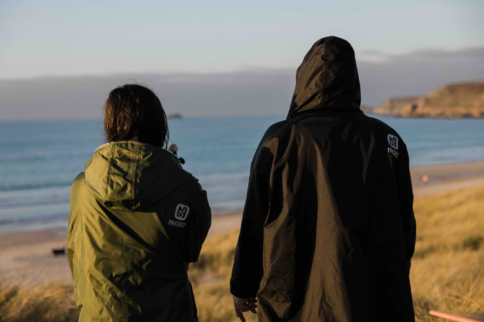 Nageuse en eau froide enveloppée dans un poncho de change imperméable doublé polaire sur une plage d&rsquo;hiver