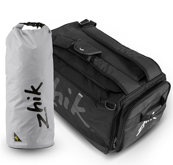 Light grey roll-top dry bag beside a black Zhik regatta holdall on a white background