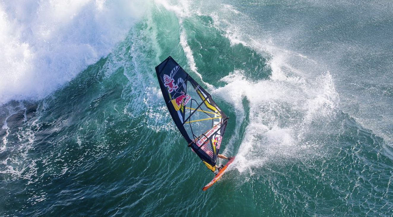 Windsurfer carving down the face of a large breaking green wave