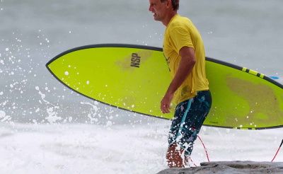 Hombre corriendo hacia el mar con una tabla de surf