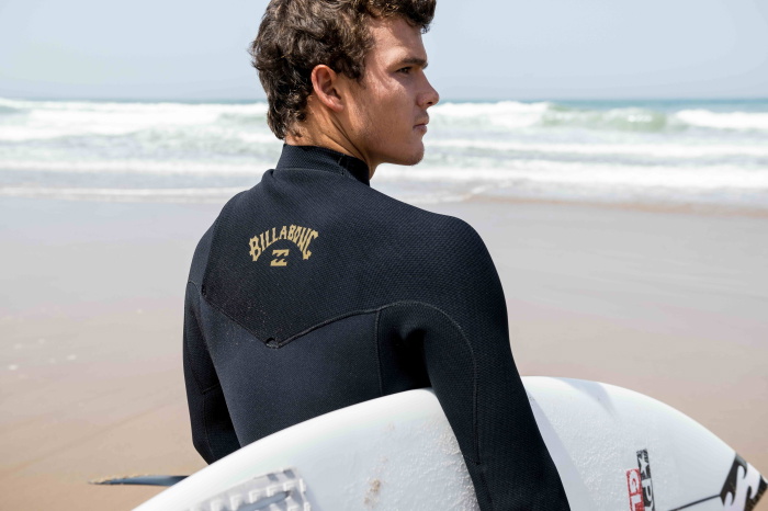 Man on beach wearing a Billabong wetsuit